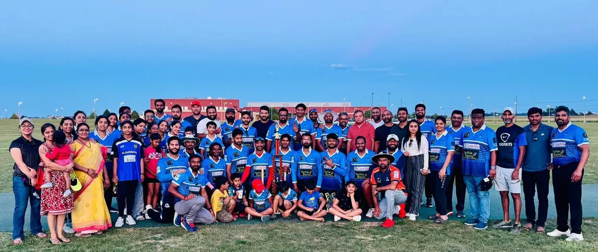 A large group of players and community members gathered on an outdoor cricket field.